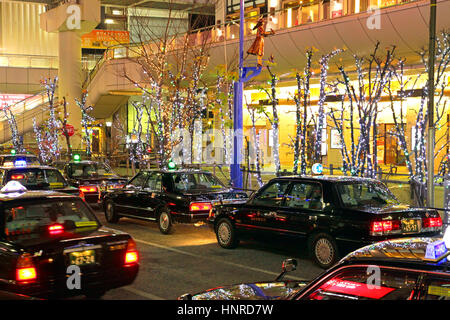 Notte di Natale Scape fila di taxi in attesa di clienti di fronte Tachikawa Stazione ferroviaria Tokyo Giappone Foto Stock