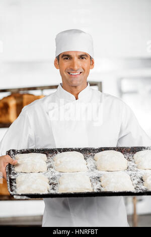 Fiducioso maschio baker holding vassoio da forno Foto Stock