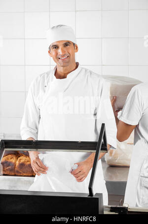 Sorridente baker pane di imballaggio nel panificio Foto Stock
