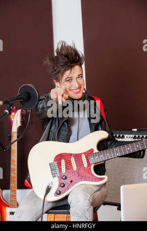 Chitarrista femmina rivolta mentre si esegue in studio Foto Stock