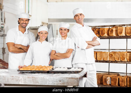 Fiducioso panettiere permanente al tavolo in forno Foto Stock