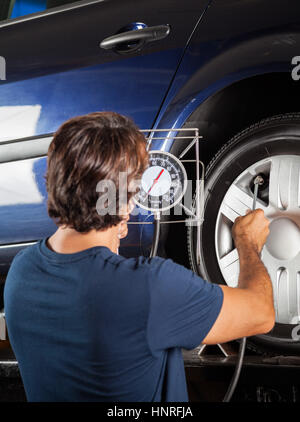 Mechanic calibro di controllo durante il gonfiaggio degli pneumatici per auto Foto Stock