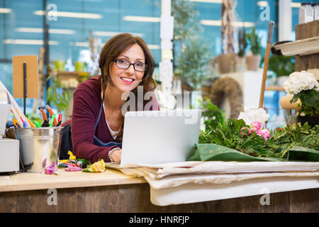 Fioraio utilizzando laptop a contatore nel negozio di fiori Foto Stock