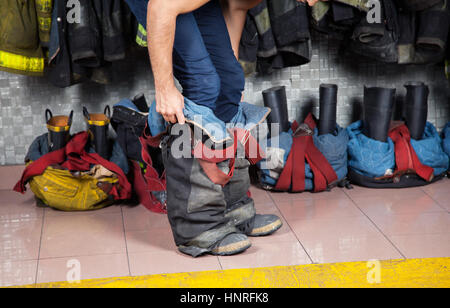 Firefighter indossano uniformi in stazione dei vigili del fuoco Foto Stock
