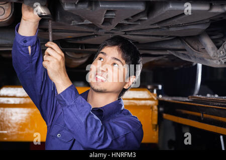 Mechanic riparazione sotto sollevato in auto Foto Stock