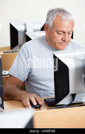 Senior uomo tramite il computer al banco in aula Foto Stock