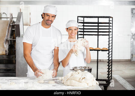 Sorridente panettiere gli impasti insieme nel forno Foto Stock