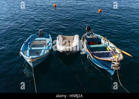 Tre piccole barche da pesca ancorate e galleggia in una calma il mare blu vicino alla costa delle Cinque Terre, Italia. Foto Stock