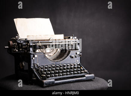 Antiquariato typewrite grunge con inserito un foglio di carta isolato su sfondo nero. Vecchio tipo di scrittore concept Foto Stock