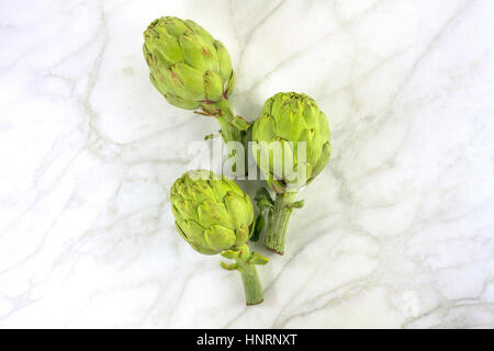 Carciofi su marmo bianco texture con copyspace Foto Stock