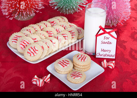 Candy Cane strippato aroma di menta piperita zucchero i cookie su un piatto di portata con i cookie su una piastra quadrata per santa con un bicchiere di latte. Nota accanto a mil Foto Stock