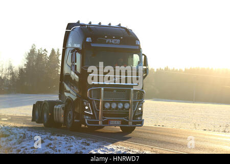 SALO, Finlandia - 6 gennaio 2017: Nero Volvo FH trattore semi di MHL Trans si muove lungo inverno autostrada nella luce dorata del tramonto. Foto Stock