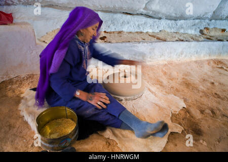 Tunisia.Matmata. Donna berbera in casa troglodita . Macinare il grano per fare di cuscus Foto Stock