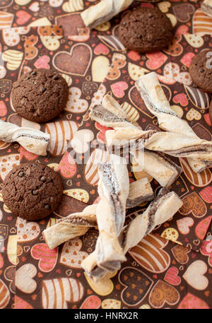 I cookie sul tovagliolo scuro con immagine di cuori vicino. Vista dall'alto. Foto Stock