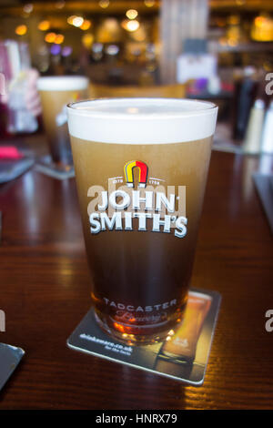 Una pinta di birra John Smiths di stabilirsi in un Yorkshire bar su una birra drinkaware mat Foto Stock
