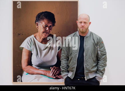 Wolfsburg, Germania. Xvi Feb, 2017. Artista sudafricano Pieter Hugo pone di fronte a una foto di Ann Salies (2013) presso la mostra fotografica "tra il diavolo e il mare blu profondo" al Kunstmuseum ("arte museo') in Wolfsburg, Germania, 16 febbraio 2017. Si tratta del primo assolo istituzionale mostra del fotografo in Germania. Hugo si concentra sui modi diversi di persone vivono insieme in dittature. Foto: Julian Stratenschulte/dpa/Alamy Live News Foto Stock