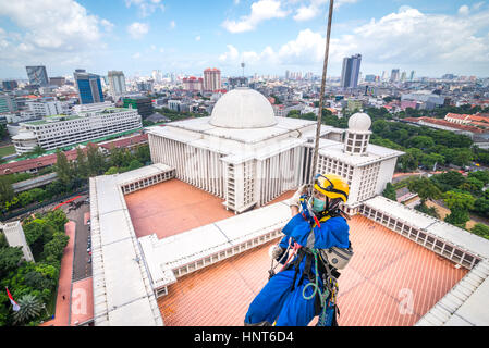 Jakarta, Indonesia. 17th Febbraio, 2017. Un lavoratore volontario scende le corde per iniziare a pulire le pareti esterne della torre alta 66,66 metri della Moschea Istiqlal a Jakarta, Indonesia. Decine di membri dei club appassionati di attività all'aperto, società di accesso alla corda e organizzazione di servizi di avventura all'aperto, si riuniscono volontariamente per ripulire la più grande moschea del sud-est asiatico per rafforzare l'unità nazionale, la solidarietà e la tolleranza. Foto Stock