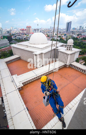 Jakarta, Indonesia. 17th Febbraio, 2017. Un lavoratore volontario scende le corde per iniziare a pulire le pareti esterne della torre alta 66,66 metri della Moschea Istiqlal a Jakarta, Indonesia. Decine di membri dei club appassionati di attività all'aperto, società di accesso alla corda e organizzazione di servizi di avventura all'aperto, si riuniscono volontariamente per ripulire la più grande moschea del sud-est asiatico per rafforzare l'unità nazionale, la solidarietà e la tolleranza. Foto Stock