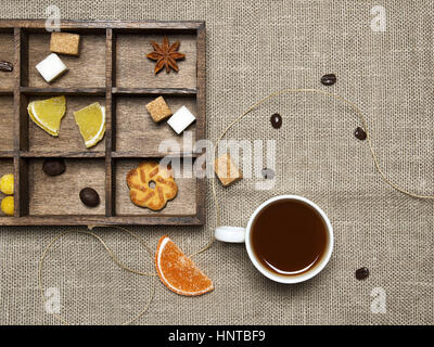 Tazza di caffè, caramelle, i chicchi di caffè su sfondo di lino Foto Stock