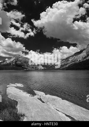 Immagine in bianco e nero del Lago Tenaya nel Parco Nazionale di Yosemite high country con in primo piano lastra di roccia e il bianco delle nuvole nel cielo Foto Stock