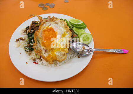Piatto di riso e carne e verdure con un uovo fritto su una piastra di colore giallo a al mercato Tailandese locale Foto Stock
