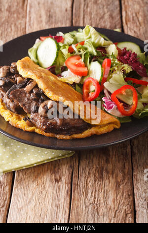 Imperiale austriaco bistecca con funghi, uova strapazzate e insalata fresca sulla piastra closeup verticale. Foto Stock