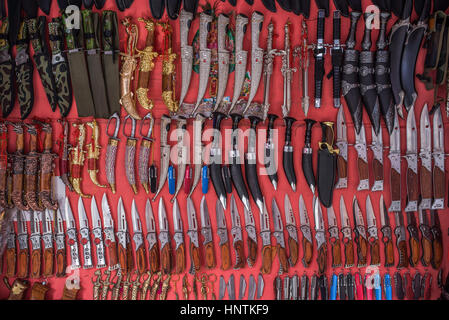 Coltelli sul display su uno sfondo di colore rosso per la vendita a Pushkar, India Foto Stock