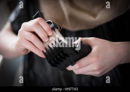 Un ragazzo avente il suo taglio di capelli con clippers e forbici. Foto Stock