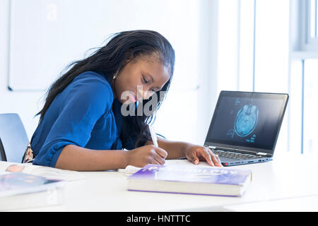 Una femmina di studente utilizzando un computer portatile e di libri di testo. Foto Stock