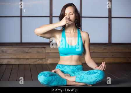 Giovane donna attraente rendendo narice alternativo di respirazione, studi Foto Stock