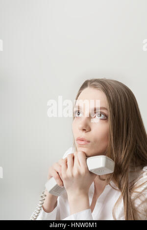 Il giovane bella con i capelli lunghi ragazza parla in ufficio tramite telefono Foto Stock