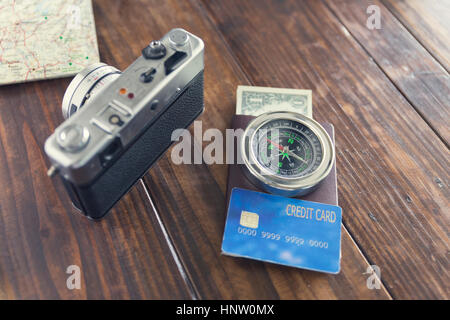 Fotocamera, Bussola passaporto e carta di credito, banconote, mappa sul tavolo di legno per uso come concetto di viaggio (vintage tono e messa a fuoco selezionata) Foto Stock