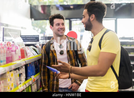 Giovane uomo giovane nel supermercato scegliendo prodotti sorridenti ragazzi acquisto Foto Stock