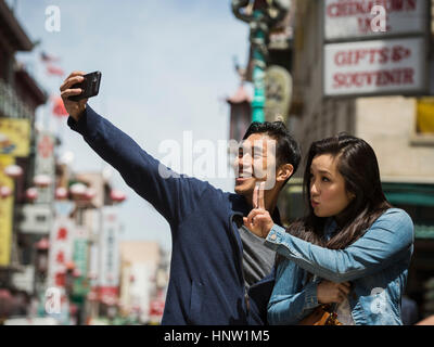 Cinese sorridente giovane in posa per telefono cellulare selfie in città Foto Stock