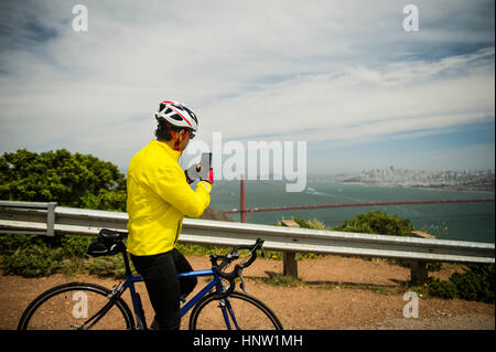 Uomo ispanico in bicicletta sul lungomare di fotografia con un telefono cellulare Foto Stock