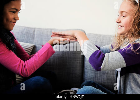Ragazze sorridenti giocando con le mani sul divano Foto Stock