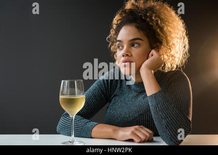 Annoiato razza mista donna che indossa un maglione bere il vino Foto Stock