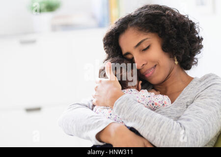 Madre ispanica abbracciando la nostra bambina Foto Stock