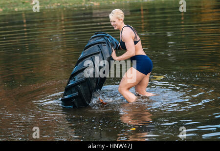 La donna caucasica di spinta pneumatico pesante nel lago Foto Stock