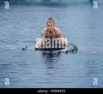 La donna caucasica sollevamento pneumatico pesante nel lago Foto Stock