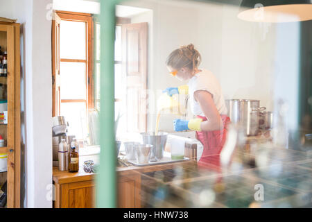 Giovane donna versando il liquido sapone di lavanda in ciotola in sapone artigianale workshop Foto Stock