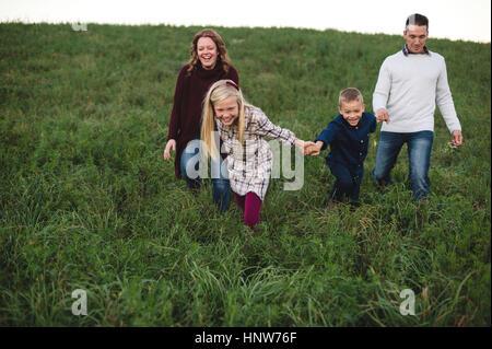 Famiglia tenendo le mani a piedi nel campo Foto Stock