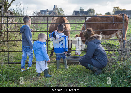 Madre e figli guardando le mucche attraverso la porta Foto Stock