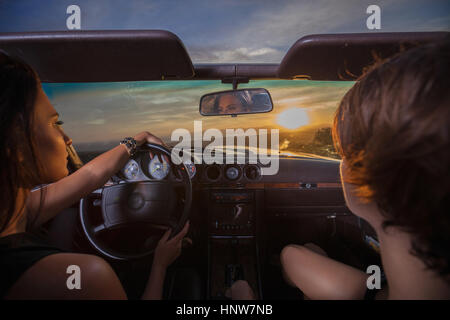Due giovani donne in autovettura convertibile, guidando lungo la strada panoramica, vista posteriore Foto Stock