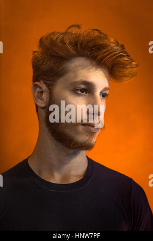 Ritratto di giovane uomo con i capelli rossi contro lo sfondo arancione Foto Stock