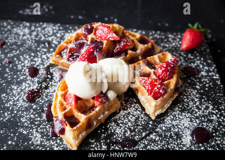 Fragole e gelato waffle su ardesia spolverati con zucchero a velo Foto Stock