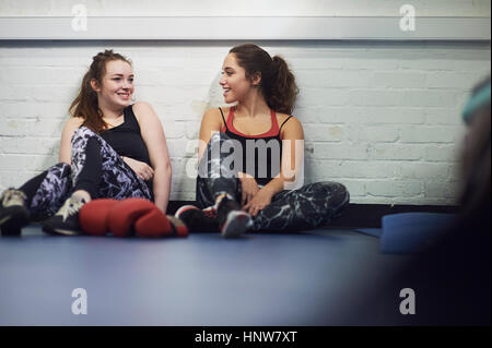 Due giovani femmine boxer seduto sul pavimento palestra in chat Foto Stock