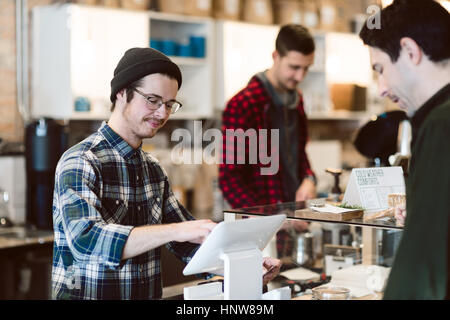 Cassiere frequentando il cliente in cafe Foto Stock