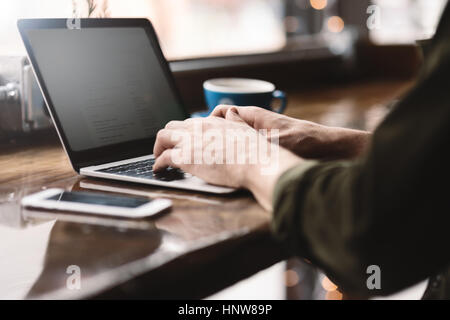 Uomo al lavoro su computer portatile presso il cafe Foto Stock