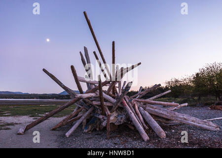 Impilati driftwood log sulla spiaggia al tramonto, Rathrevor Spiaggia Parco Provinciale, Isola di Vancouver, British Columbia, Canada Foto Stock